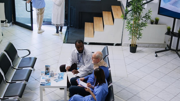 A diverse group of healthcare professionals collaborating in a modern office setting. Some are looking at computer screens, while others are discussing telehealth strategies around a table. The image conveys a sense of teamwork and innovation in healthcare.