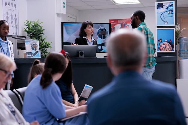 A diverse group of doctors and nurses collaborating and reviewing patient data on a large interactive screen within a modern telemedicine hub.