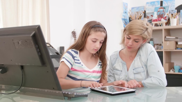 A teacher reviewing data analytics reports on laptop while the student is solving problems on a tablet.