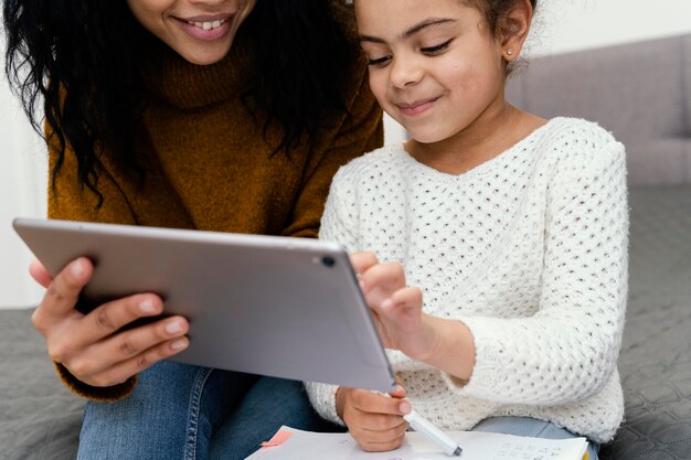A teacher providing one-on-one assistance to a student using a digital tablet in a classroom setting. The focus is on the interaction and personalized support, highlighting the teacher's role in facilitating digital learning.