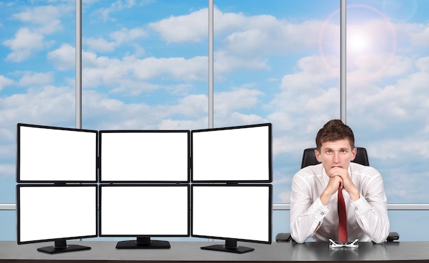 A person sitting at a desk, looking stressed and overwhelmed, with multiple screens displaying work-related information, symbolizing burnout and the need for better work-life balance.